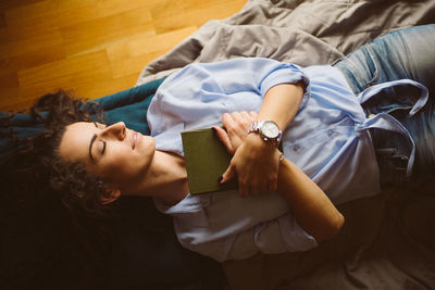 Young woman with book lying in light room