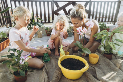 Mother and daughters planting flowers on roof terrace together