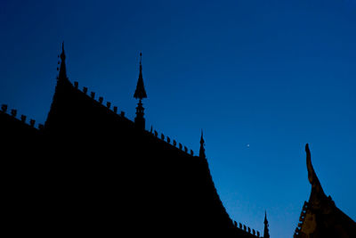 Low angle view of silhouette building against clear blue sky