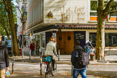 Rear view of people walking on street amidst buildings