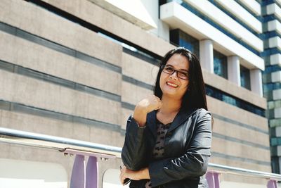 Portrait of smiling businesswoman standing against building