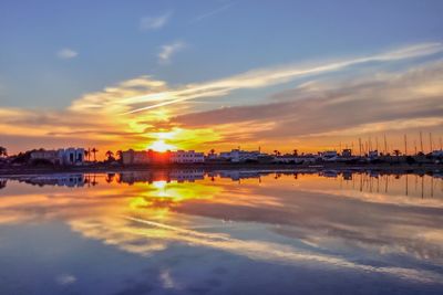 Scenic view of sea by buildings against sky during sunset