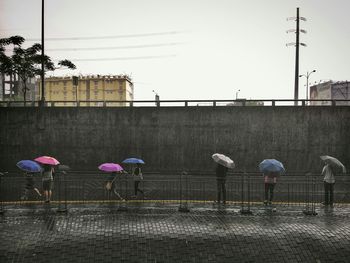 People by railing against clear sky