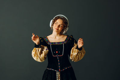 Portrait of young woman standing against black background