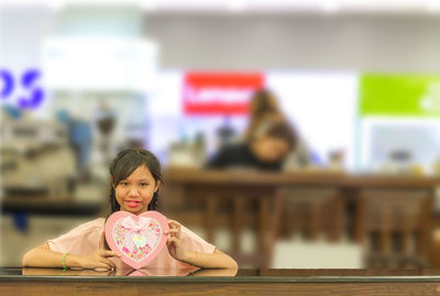 Portrait of a smiling girl sitting on table