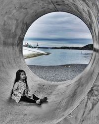 Portrait of woman sitting on beach against sky