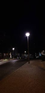 Empty road against illuminated buildings at night