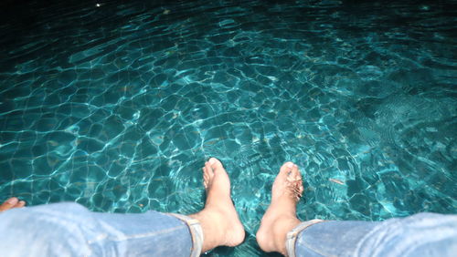 Low section of man relaxing in swimming pool