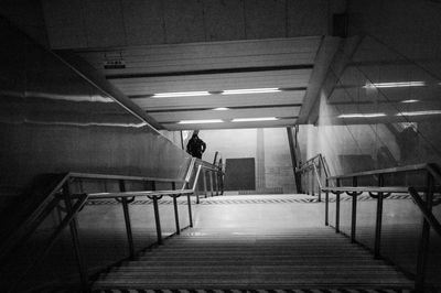 Rear view of man walking on staircase in building