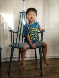 Full length of boy sitting on chair at home