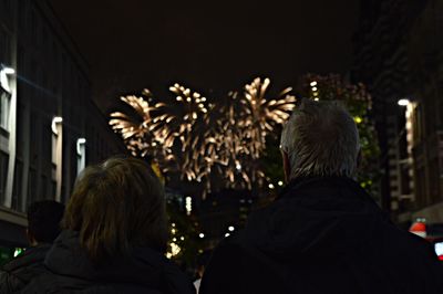 Rear view of people with arms outstretched at night