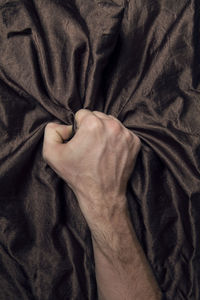 Close-up of man hand on bed