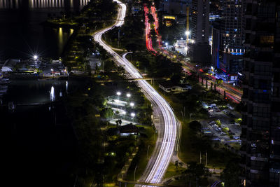 High angle view of illuminated buildings in city at night with car light in both ways 