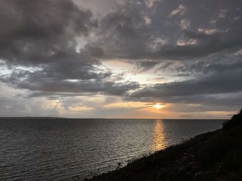 Scenic view of sea against dramatic sky during sunset