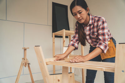Full length of woman standing against wall at home