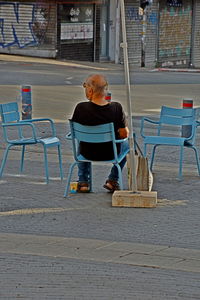 Man sitting on chair at street