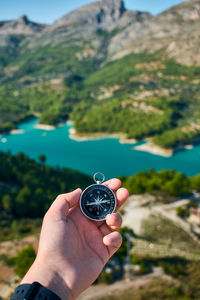 Midsection of person holding sunglasses against mountain