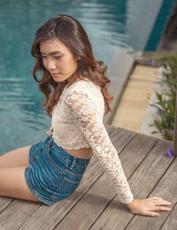 Young woman looking away while standing on wood