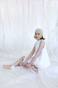 Full length portrait of woman sitting on white sofa