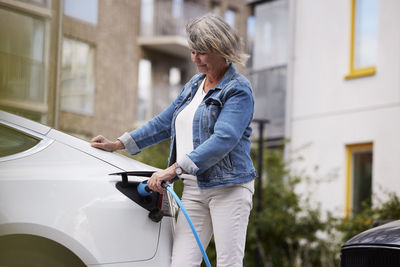 Senior woman charging electric car