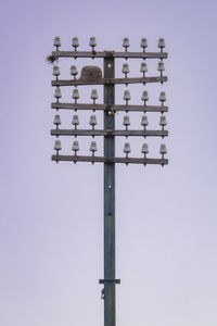 Low angle view of birds perching on pole against sky