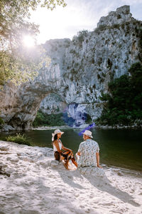 People sitting on rock by water