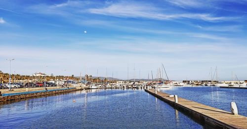 Sailboats moored at harbor against blue sky