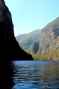 Scenic view of river by mountains against clear sky