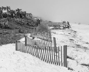 Fence on snow covered field against sky