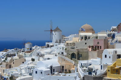 Traditional windmill in town at santorini against clear blue sky