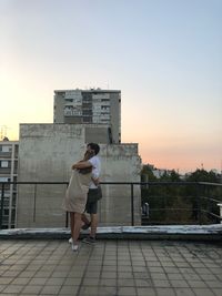 Woman standing by building against sky in city