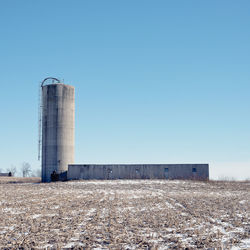 Low angle view of tower against clear blue sky on sunny day during winter