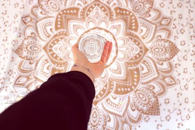 Low angle view of hand holding crystal ball against ceiling