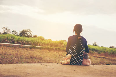 Rear view of woman sitting on field