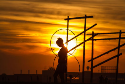 Silhouette woman with plastic hoop during sunset