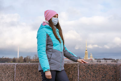 Woman with umbrella standing against sky during winter