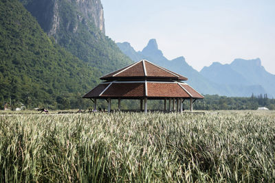 House on field by mountains against sky