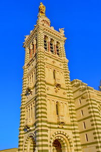 Low angle view of bell tower against blue sky