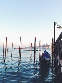 Wooden posts in water against clear sky