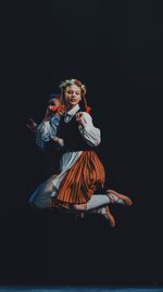 People jumping while dancing against black background