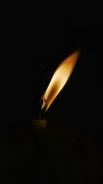 Close-up of lit candle in darkroom