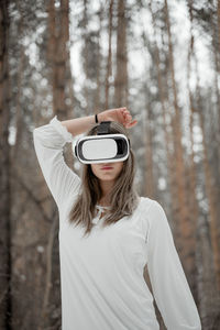 Woman wearing virtual reality simulator against trees outdoors