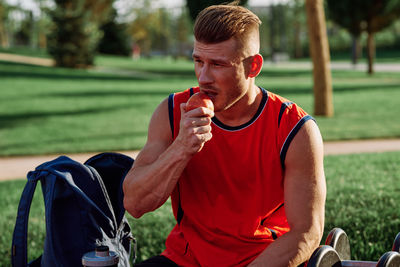 Side view of young man blowing bubbles in park