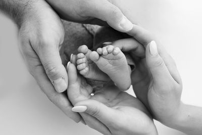 Cropped image of baby holding hands against white background