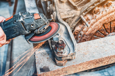 Angle grinder close-up. a man's hand holds a manual sander near a vintage machine. sparks.