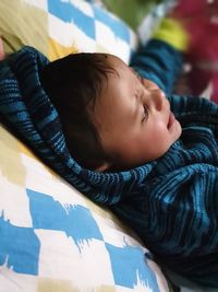 High angle view of cute boy looking away while lying on bed