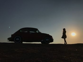 Side view of silhouette woman standing on car against sky