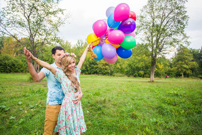 Rear view of woman holding balloons on field