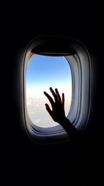 Close-up of hand through window in airplane