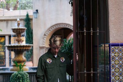 Man wearing sunglasses while standing metal gate